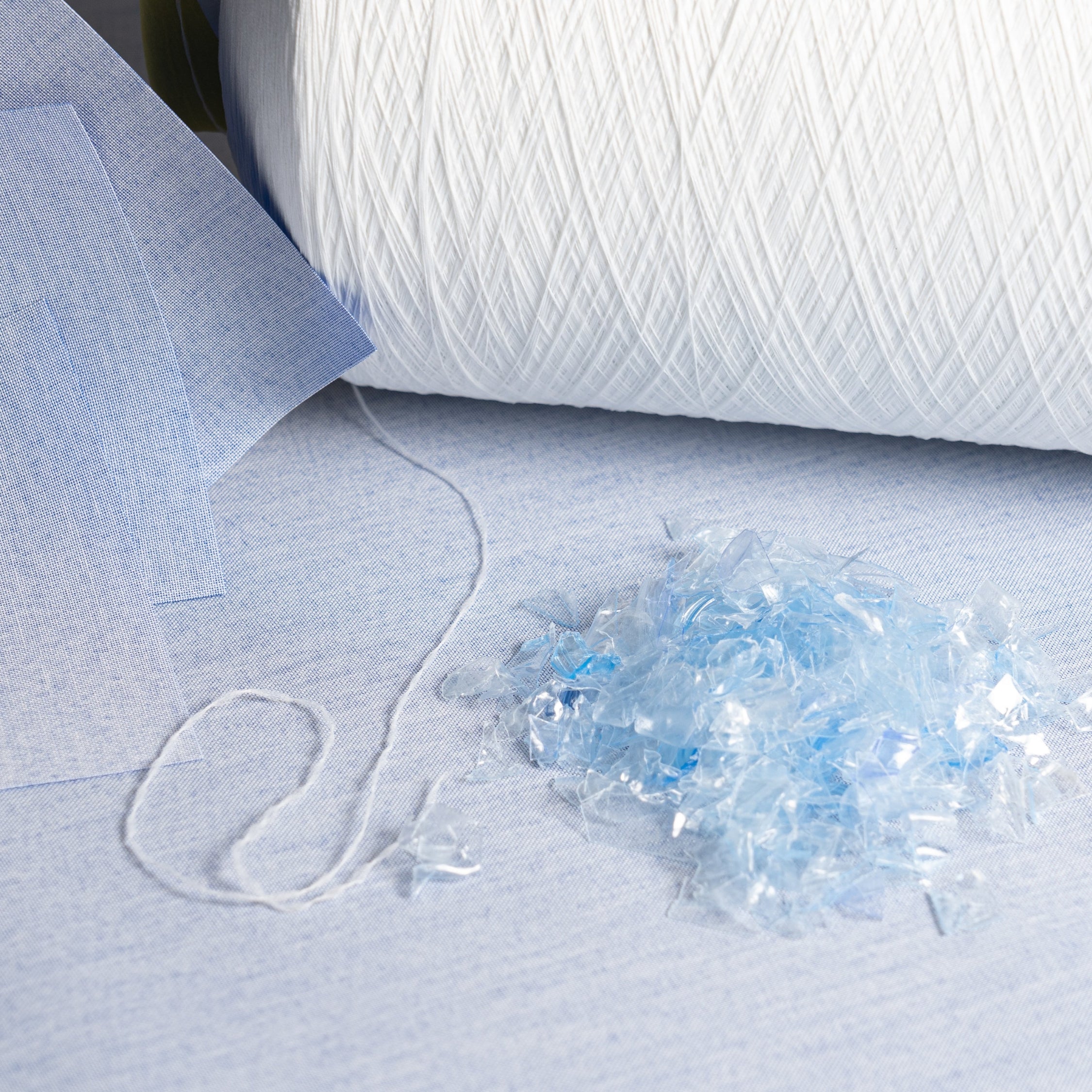 Close-up of white yarn on a textured surface with a small pile of yarn fibers.